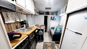 A compact kitchen with a stove, sink, and a small dining area. - Vintage Rv & Spa Experience for 3 (Dover)