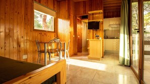 Un interior de madera con comedor, cocina y ventanas grandes.
