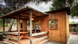 Una cabaña de madera con un porche cubierto, número 151, que cuenta con una mesa y bancos de madera.