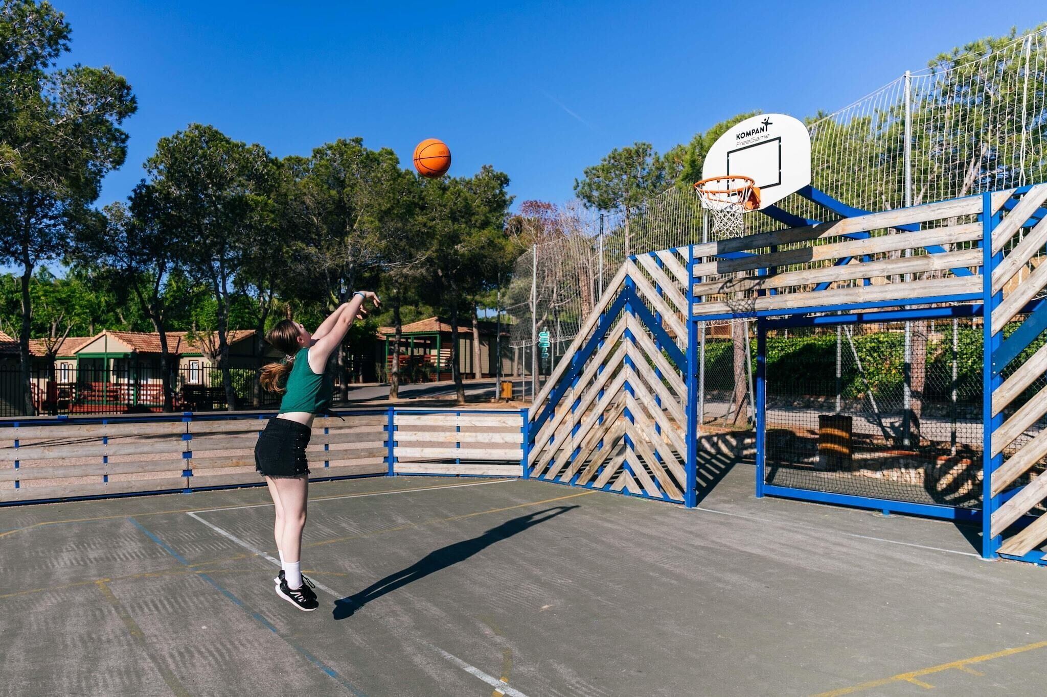 A basketball court with a hoop and a netted enclosure.