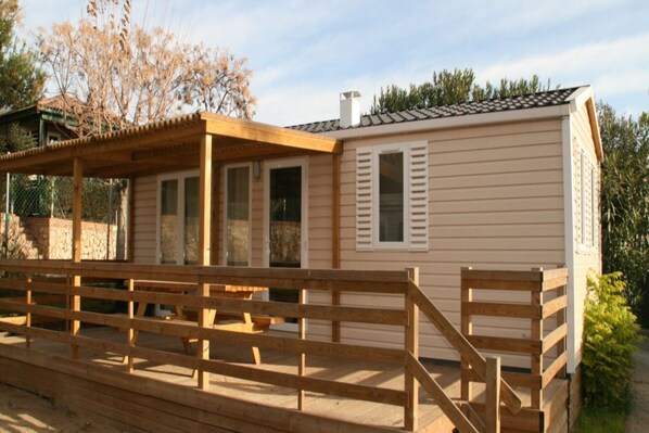 Ein Bungalow mit überdachter Veranda und einem eingezäunten Außenbereich.