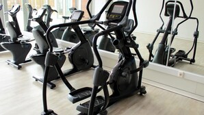 A gym with multiple stationary bikes and elliptical machines.