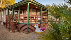 A small, single-story building with a covered porch, a wooden ladder, and a colorful inflatable unicorn.