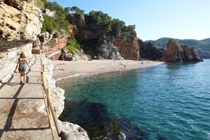 A coastal walkway leading to a beach with clear water, rocky cliffs, and greenery. - Bungalow near Pals Beach & Pool (Pals)
