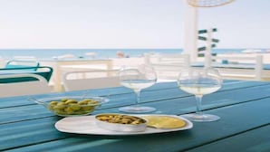 Una mesa con comida y bebidas, con vista a la playa.