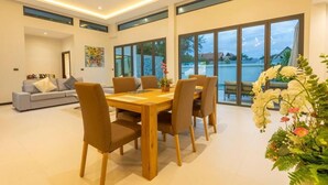 Ein stilvoller Essbereich mit Holztisch und -stühlen, einer Couch und großen Fenstern mit Meerblick.