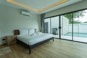 Een moderne slaapkamer met een groot bed, een nachtkastje, een airconditioningapparaat en een glazen schuifdeur naar een zwembad.