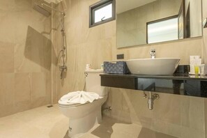 Een moderne badkamer met een groot bad, toilet en een wastafel met spiegel.