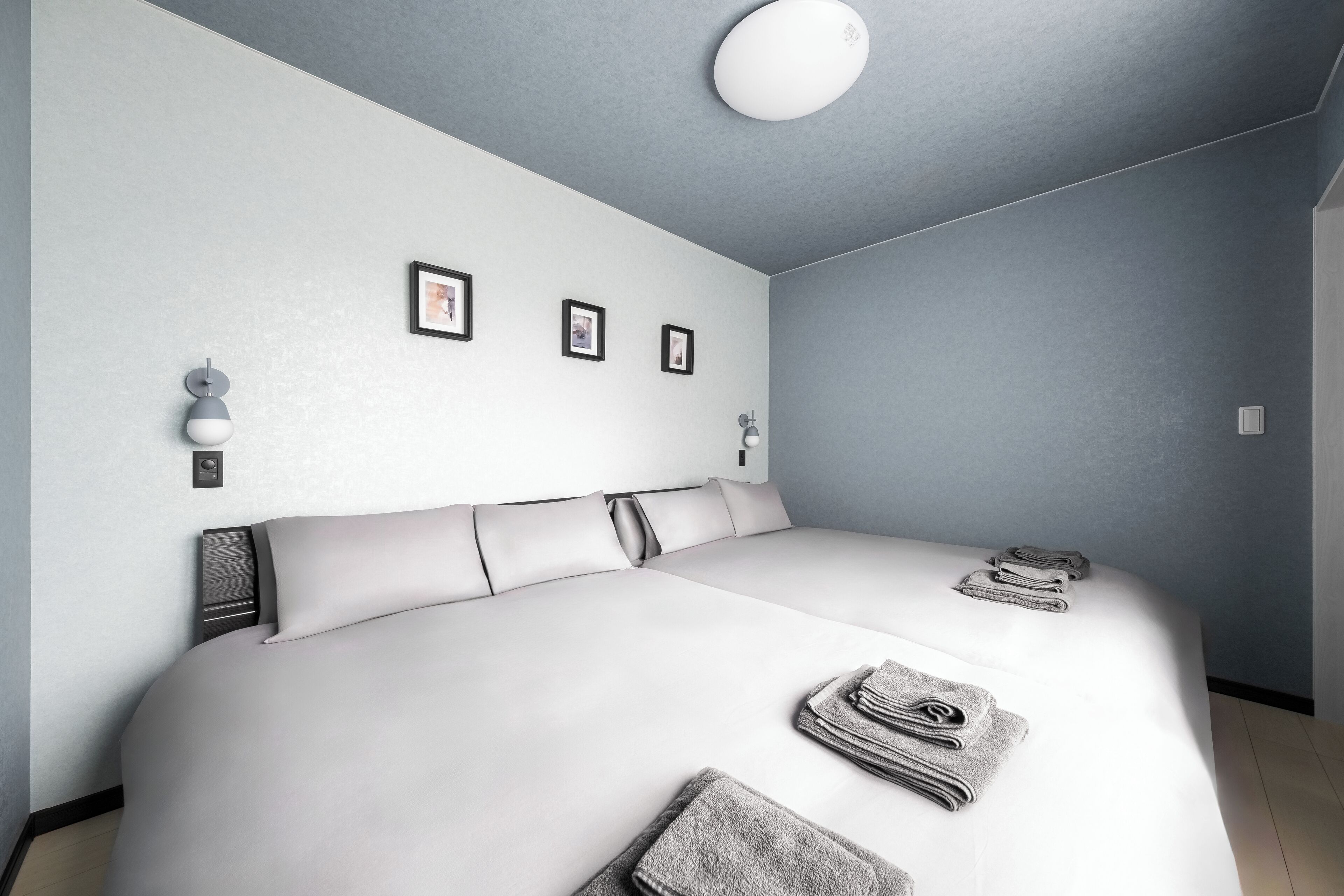 Ein modernes Schlafzimmer mit einem großen Bett, einer Deckenleuchte und einem an der Wand befestigten Bilderrahmen.