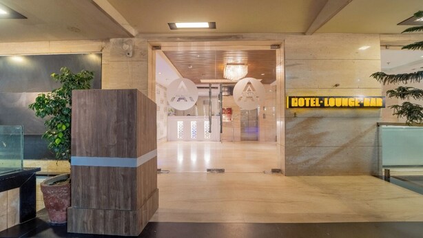 Un hall d’hôtel avec un comptoir d’accueil, une colonne en bois et un panneau indiquant l’emplacement du bar-salon de l’hôtel.