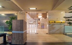A hotel lobby with a reception desk, a wooden column, and a sign for the hotel lounge-bar. - Hotel Aditya Park Regent (Jaipur)