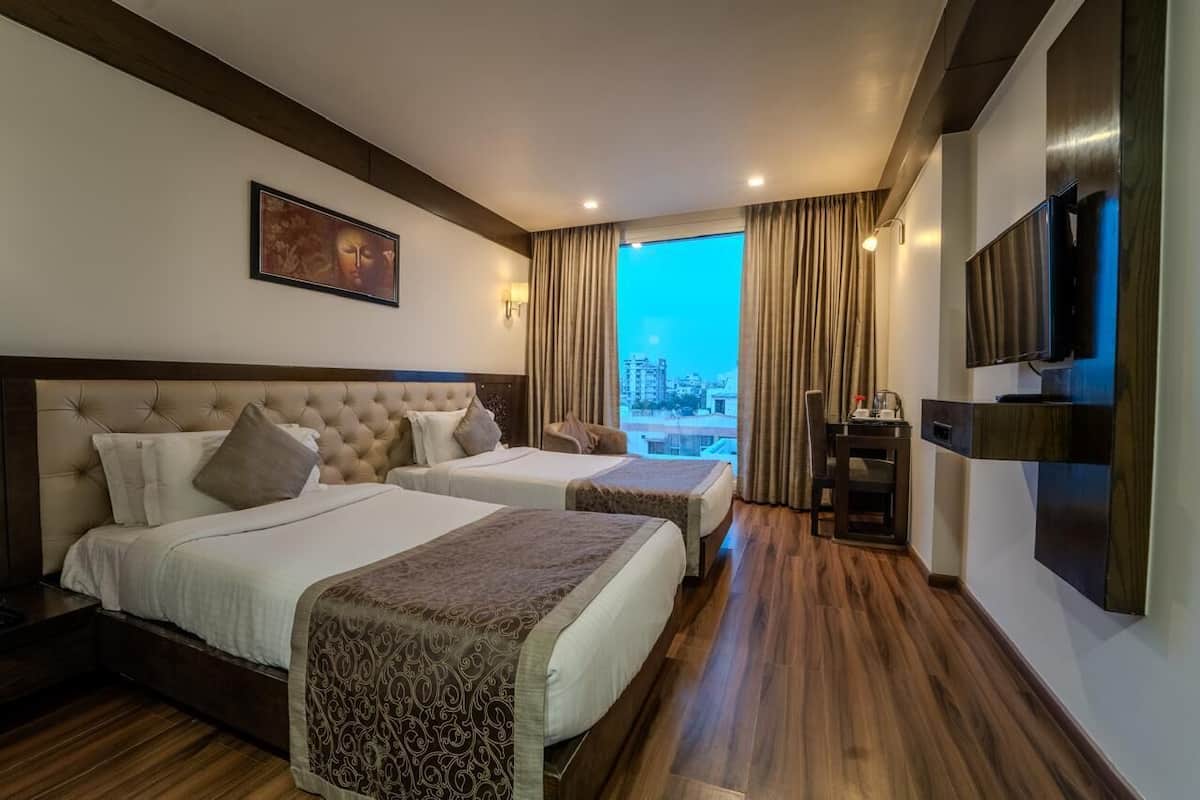 Une chambre d’hôtel avec deux lits, une télévision, un bureau et une vue sur la ville.