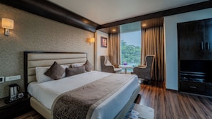 Une chambre d’hôtel avec un grand lit, une télévision, une petite table avec des chaises et une vue sur l’extérieur par la fenêtre.