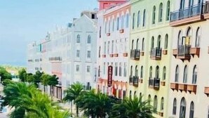 A street lined with colorful buildings, palm trees, and a clear blue sky. - Quynh Anh Hotel Ha Long (Bai Chay)