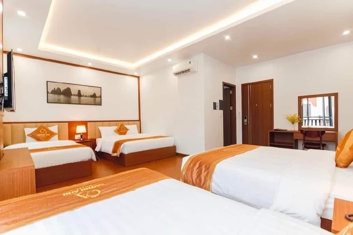 A hotel room with two beds, a desk, a chair, and a TV.