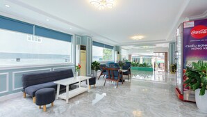 A modern hotel lobby with a seating area, a Coca-Cola advertisement, and large windows offering a view.