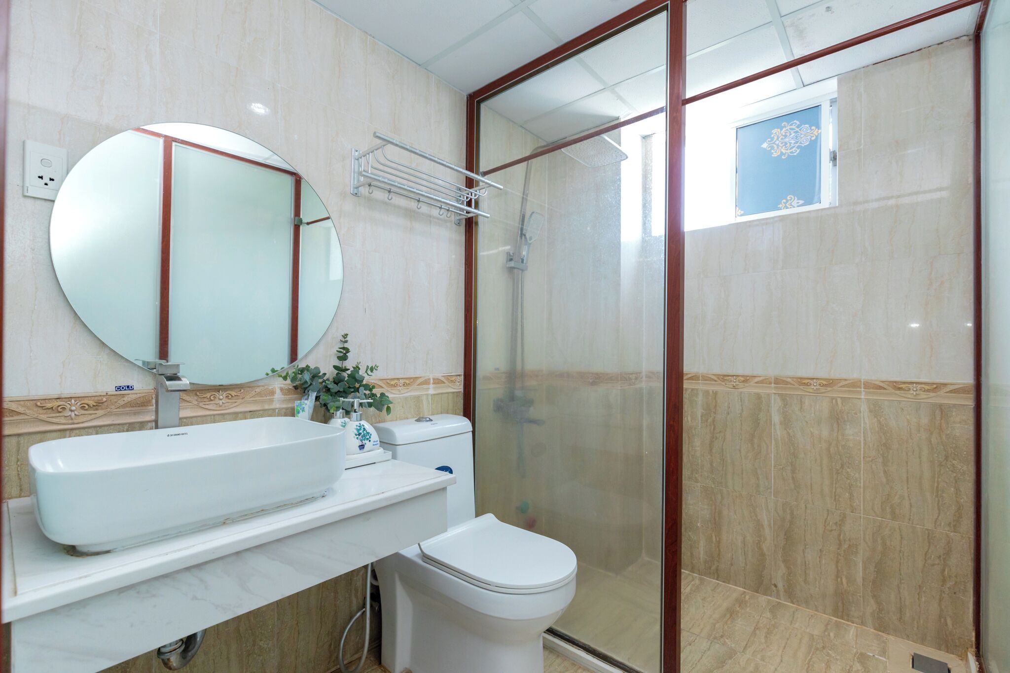 Une salle de bain avec un grand miroir, un lavabo, des toilettes et une douche à parois de verre.