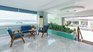 A modern lobby with a seating area, a glass wall, and a view of the street.