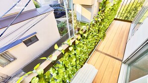 Een balkon met een houten vloer en een rij groene planten.