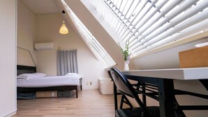 A modern room with a bed, a desk, and a chair. There is a window with blinds, a hanging light, and a plant on the desk. - 7:00 IN/19:00 OUT】4min丨Newly renovated丨Four minutes from Shinjuku Station by train, eight minutes from 丨Maximum 6 people丨Dedicated bathroom and kitchen (中野区)