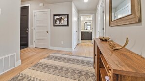 A hallway with a wooden console table, a rug, and a framed picture on the wall.