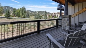 A wooden deck with a view of a mountain range and a building in the background.