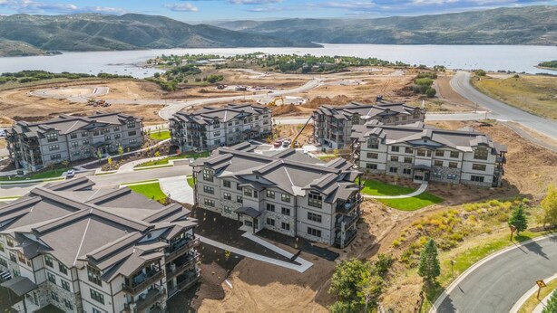 A residential area with multi-story buildings, a road, and a lake in the background.