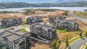A residential area with multi-story buildings, a road, and a lake in the background.