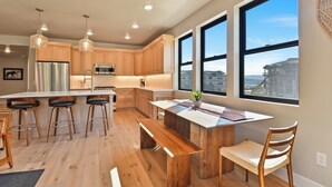A modern kitchen with wooden cabinets, stainless steel appliances, and a large island with bar stools.