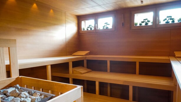 Un sauna en bois doté de plusieurs bancs et d’un plateau en pierre.