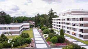 Un bâtiment moderne doté d’une cour intérieure, entouré de verdure et surplombé d’un ciel dégagé.