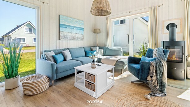Un moderno salón con un sofá azul, una mesa de centro blanca y una chimenea. Una ventana grande ofrece vistas al exterior.