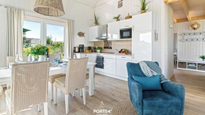 Una cocina moderna con armarios blancos, un comedor con sillas de mimbre y un sillón azul.