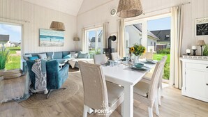 Amplia sala de estar con una mesa de comedor, sillas de mimbre y un sofá.