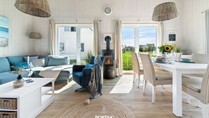 Un salón acogedor con sofá, mesa de comedor, lámparas de mimbre y chimenea.