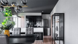 A modern kitchen with a dining area, featuring a black dining table, grey chairs, and a yellow vase with green plants. - THE OBSIDIAN  (Sapporo)