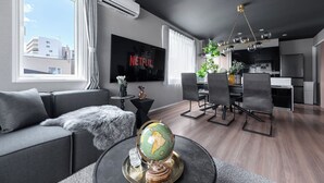 A modern living room with a sofa, a globe on a table, and a dining area with chairs and a chandelier. - THE OBSIDIAN  (Sapporo)