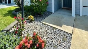 A residential house with a front porch, a small garden with flowers, and a clear blue sky. - Dessert First - Cozy 2/2 in The Village of DeLuna Accepts a Small Dog with pre-approval (The Villages)
