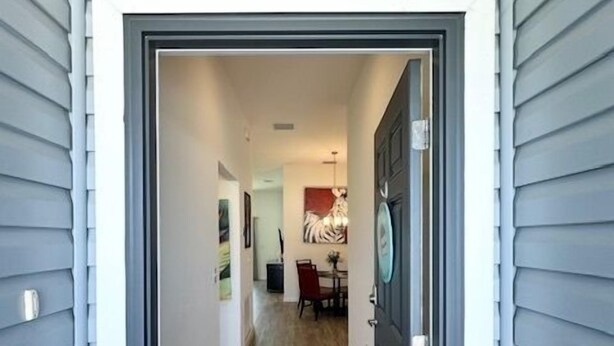 A hallway with wooden flooring leading to a dining area with a red chair and table. - Dessert First - Cozy 2/2 in The Village of DeLuna Accepts a Small Dog with pre-approval (The Villages)
