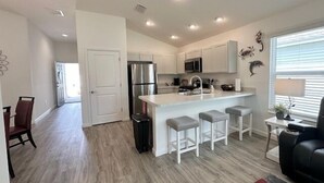A modern kitchen with a central island, stainless steel appliances, and a bar seating area. - Dessert First - Cozy 2/2 in The Village of DeLuna Accepts a Small Dog with pre-approval (The Villages)