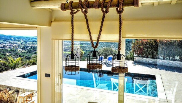 A pool area with a view of a cityscape, a pergola with ropes, and hanging birdcages. - Spacious 4 Bedroom Villa & Apartment Suite, Private Pool and Fantastic Views (Calonge)