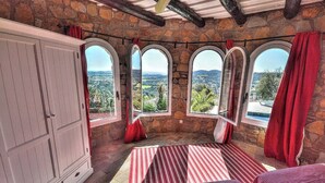 A bedroom with stone walls, large arched windows, and a view of the countryside. - Spacious 4 Bedroom Villa & Apartment Suite, Private Pool and Fantastic Views (Calonge)