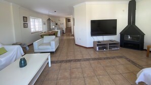 A living room with a TV, fireplace, and a staircase leading to another level. - Pura Vida, Casa con Preciosas Vistas una Piscina Maravillosa Ubicación Perfecta (Candelaria)
