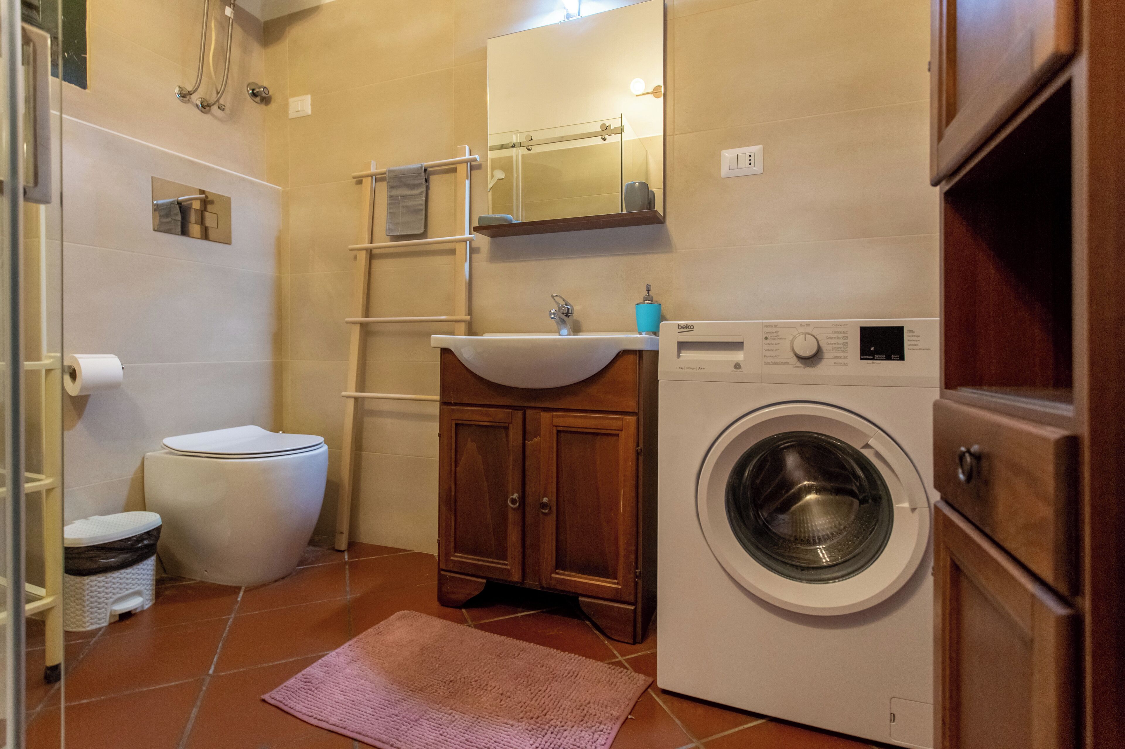 A compact bathroom with a toilet, sink, and washing machine.