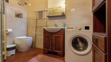 A compact bathroom with a toilet, sink, and washing machine.
