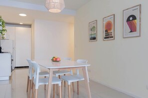A modern dining area with a white table and chairs, a fruit bowl, and two framed artworks on the wall. - MOT  Rentals+ Segui 3972 'C' - Loft Palermo (Buenos Aires)