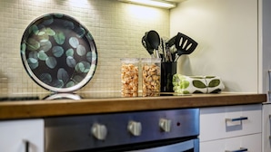 A kitchen counter with a pot lid, two jars of dried herbs, and a container of utensils. - Prime 3 Bedrooms Flat – Perfect for Families & Groups (Greater London)