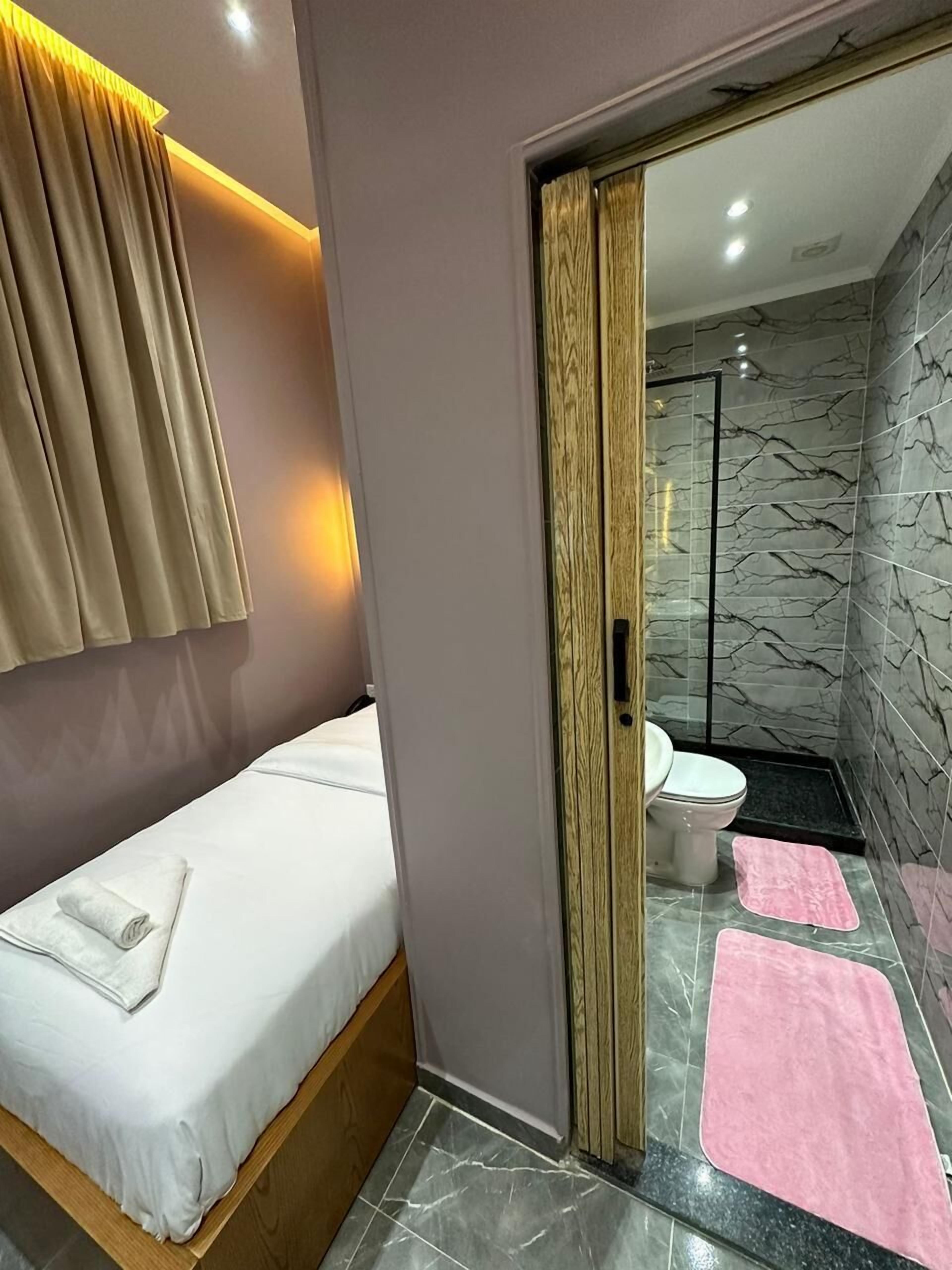 Ein modernes Badezimmer mit Duschkabine aus Glas, Toilette und rosa Badteppichen.