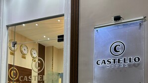 Een hotelentree met een glazen deur, een receptiebalie en een bord waarop 