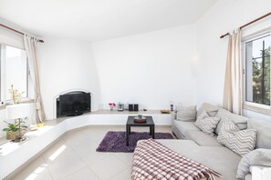 A modern living room with a sofa, a television, a small table, and a fireplace.